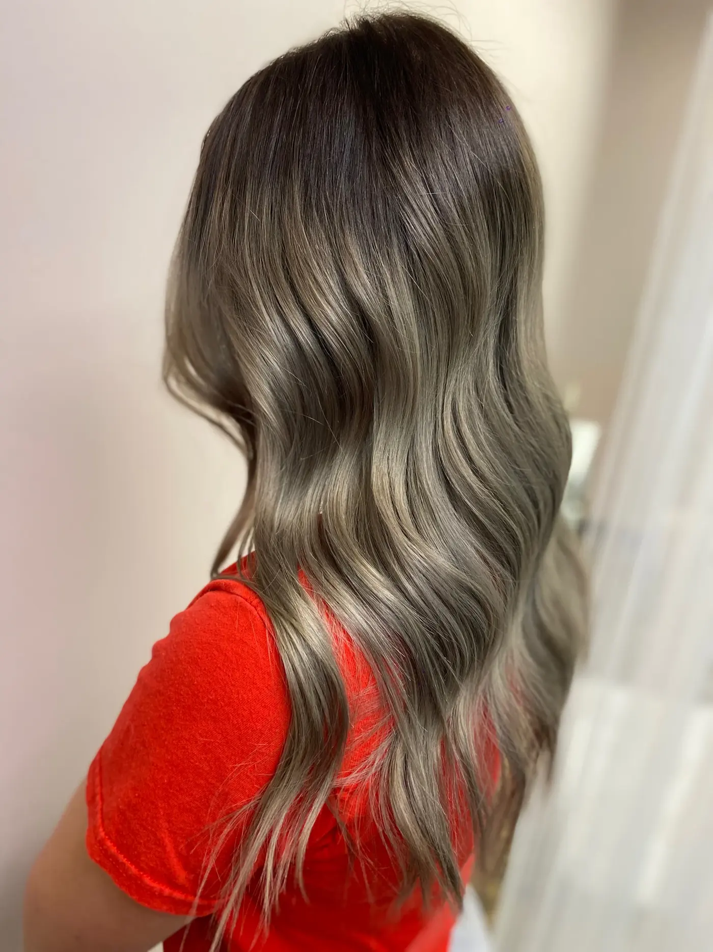 Long ash-blonde dimensional color with soft waves, styled by Alexis